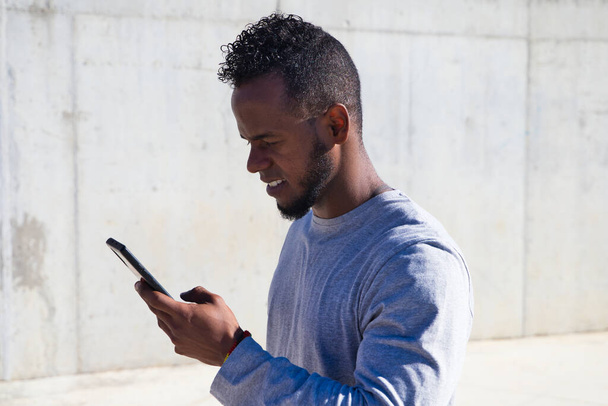 афро-американец смотрит на свой мобильный телефон, потому что он получил информацию по смс или электронной почте - Фото, изображение