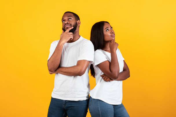 Black man and woman thinking on yellow background - Foto, Imagen