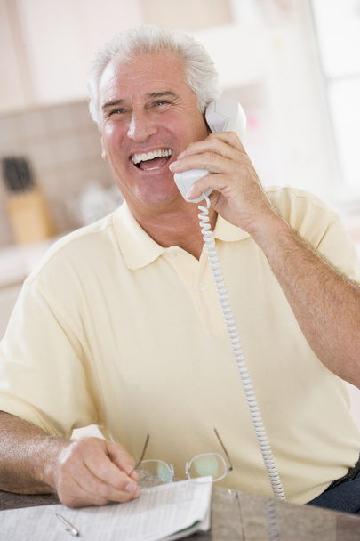 Man in kitchen on telephone laughing - Fotó, kép