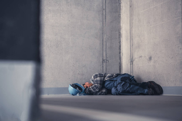 彼のシフト中に仕事で生コンクリートの上で眠る排気建設労働者。身体的・精神的課題テーマ. - 写真・画像
