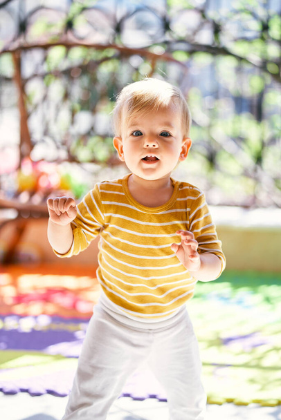 Criança pequena fica em um tapete colorido na varanda - Foto, Imagem