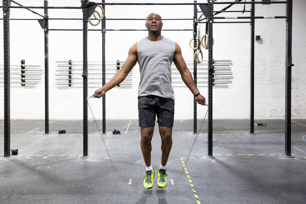 Jeune athlète masculin sautant à la corde dans la salle de gym. Concept de soins corporels. - Photo, image