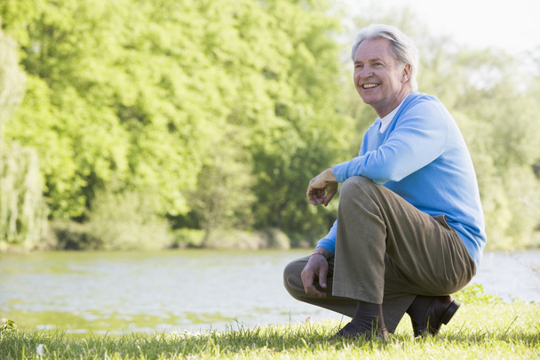 Man outdoors at park by lake smiling - Photo, image