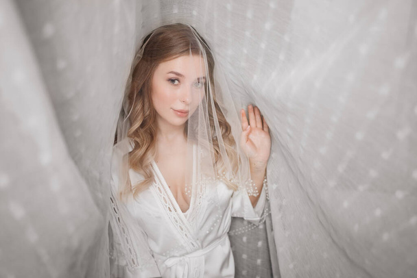gentle morning of the bride. beautiful young woman in veil under a white curtain - Foto, Imagem