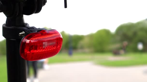 Luz trasera led intermitente montada en un primer plano de bicicleta durante el día. La parte posterior de la bicicleta con una luz de advertencia de marco rojo - Imágenes, Vídeo