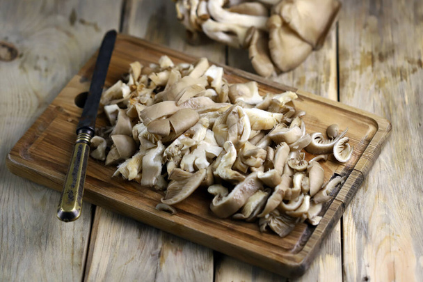 Нарезанные устричные грибы на деревянной доске. - Фото, изображение