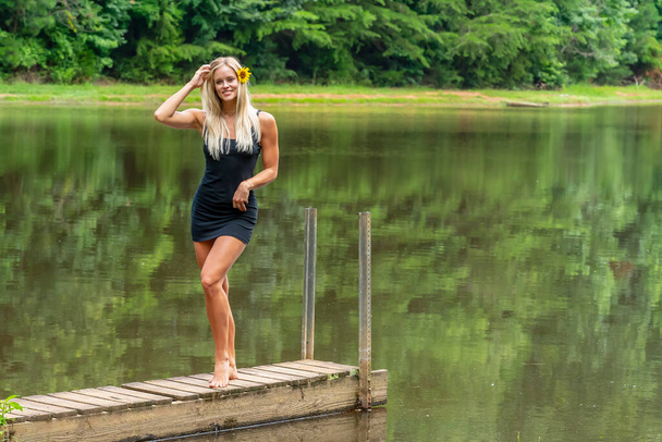 Un magnifique modèle blond pose à l'extérieur près d'un étang tout en profitant d'une journée d'été - Photo, image