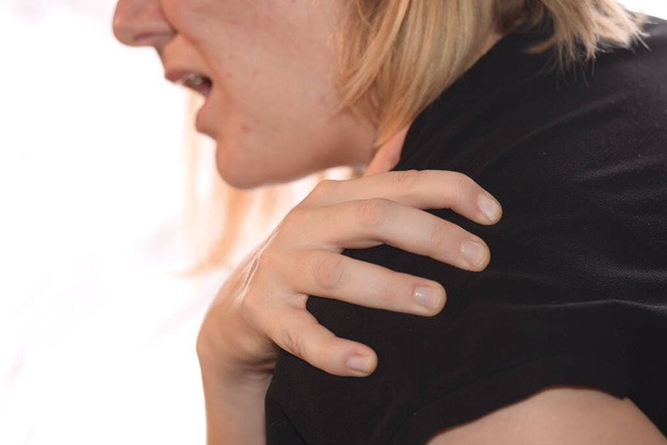 woman with pain in the shoulder holding the painful area - Photo, Image