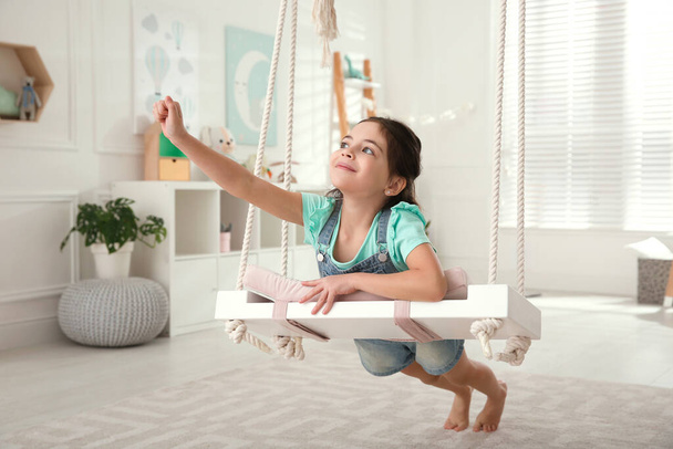 Cute little girl playing on swing at home - Foto, Bild
