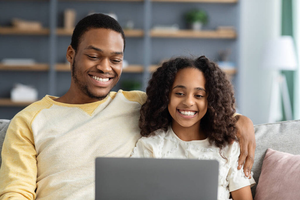 Closeup of happy black father and kid using laptop - 写真・画像