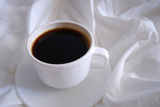 Cup of coffee on white bed linen. - Foto, immagini