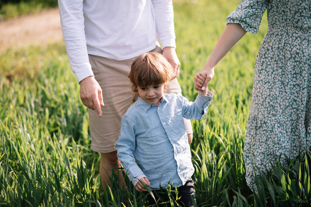 Little boy 3 years old spends time with parents in grass in park, happy childhood concept - Photo, Image