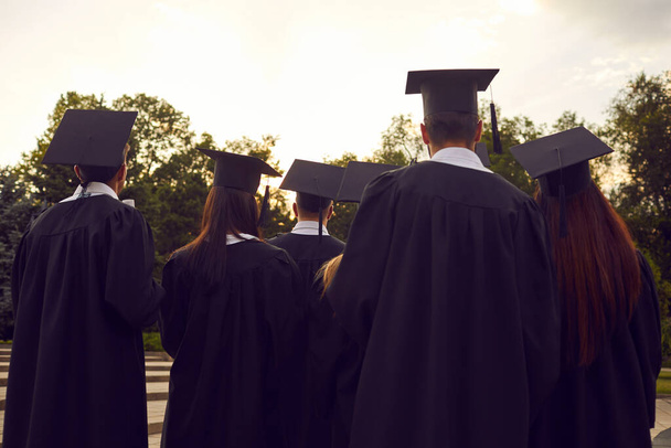 Back view of college or university graduates in black caps and gowns at graduation ceremony - Foto, Imagen