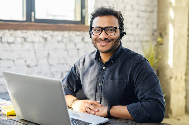 Helpful and friendly mixed-race male employee wearing headset - Valokuva, kuva