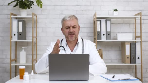 Hombre terapeuta hablando con el paciente de consultoría portátil en línea en la clínica - Imágenes, Vídeo