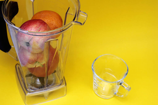 Healthy food. Vitamin food. Fruits in a blender on a yellow background. apple and orange - Photo, image