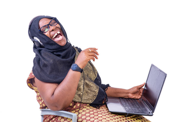 bella donna d'affari musulmana ridere seduto su sfondo bianco in comunicazione utilizzando cuffie e laptop. - Foto, immagini