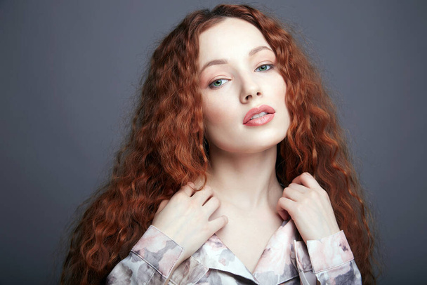 beautiful young woman with curly red hair and make-up. pretty girl in silk pijamas - Foto, afbeelding
