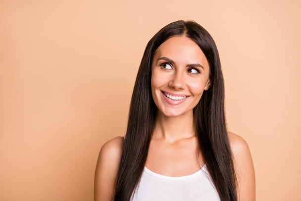Portrait of optimistic brunette girl wear white top look empty space isolated on beige color background - Fotografie, Obrázek