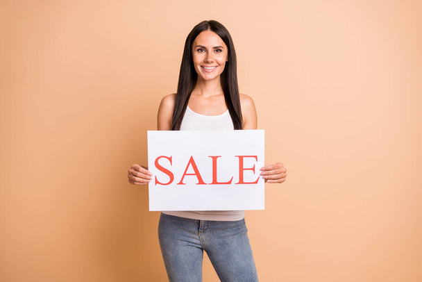 Photo portrait of girl holding sale sign with two hands isolated on pastel beige colored background - Fotoğraf, Görsel