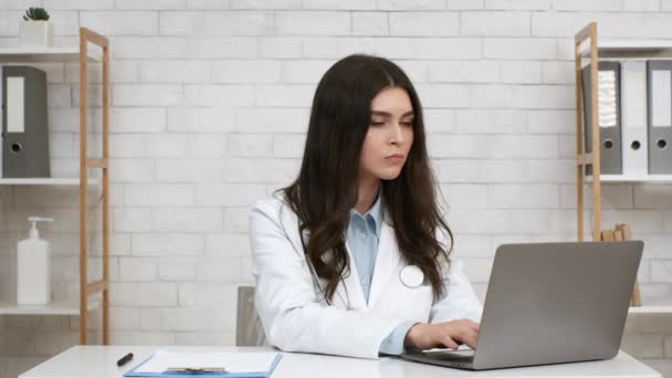 Female Physician Nodding Head To Laptop Consulting Patient Online Indoor - Кадры, видео