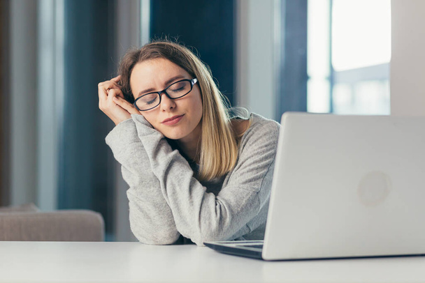 uupunut nainen työssä haukottelee tuskallisista tunteista, jotka johtuvat väärästä asennosta, istumisesta, pitkästä istumisesta kannettavassa fibromyalgiassa, nukahtaa tietokoneeseen - Valokuva, kuva