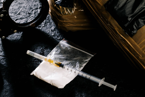 Heroina w strzykawce na ciemnej podłodze cementowej. Substancja uzależniająca, narkotyk, nielegalna rzecz, pojęcie niebezpiecznego narkotyku. - Zdjęcie, obraz