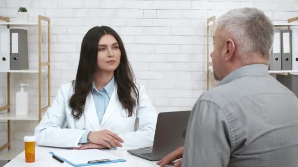 Terapista donna che consulta il capo anziano di annuire del paziente maschio in ufficio - Filmati, video