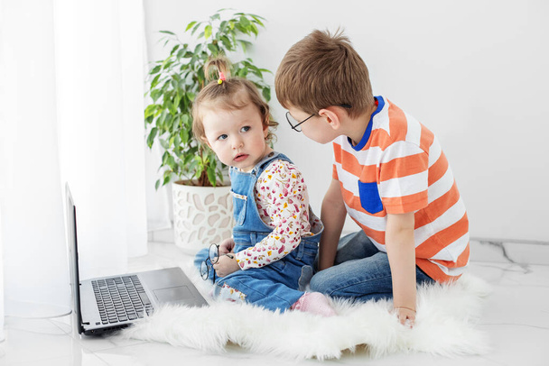 Brother and sister are watching videos online. Preschool age. Family, childhood, internet and home concept - 写真・画像