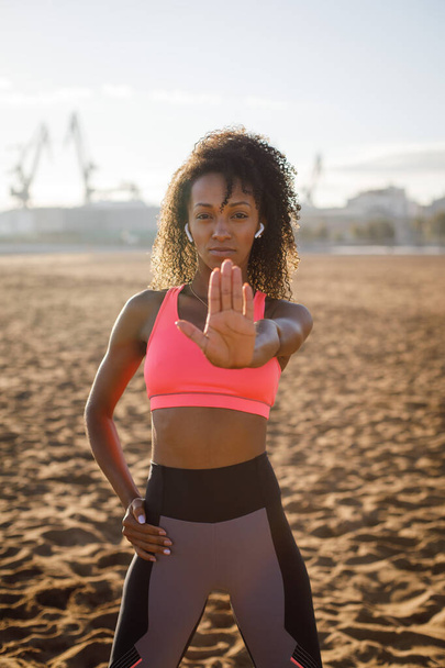 Fitness workout determination and motivation against laziness concept. Female sporty black woman doing stop gesture. - Photo, Image
