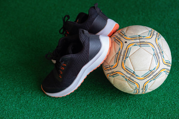 Waiting for the canvas foot to touch the black football and a white ball on green artificial turf. - 写真・画像