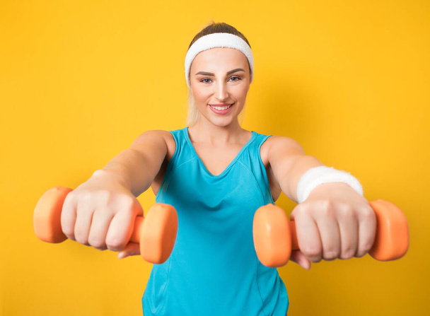 Closeup fit woman training gym with dumbbell, isolated on yellow background. Close up of beautiful sportswoman lifting weights. Fitness motivation. 80s styling. Studio shot - Fotoğraf, Görsel