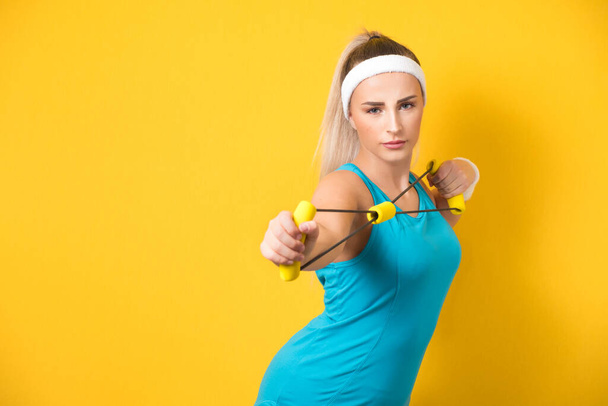 Fitness woman performs exercises for muscles hands with resistance band, isolated on white background. Half length of fit sportswoman exercising with expander. Strength motivation. Studio shot - Fotó, kép