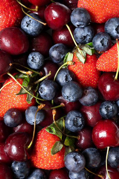lots of strawberries, cherries and blueberries. juicy summer background with fruit. - Foto, imagen