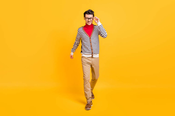 Фотографія повного розміру молодого впевненого чоловіка щаслива позитивна посмішка йдіть крок за кроком дотик окуляри ізольовані на жовтому кольорі
 - Фото, зображення