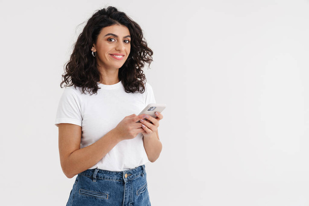 Gyönyörű fiatal mosolygós nő segítségével mobiltelefon elszigetelt fehér háttér - Fotó, kép