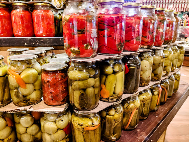 Frascos de vidrio con verduras y frutas saladas, en escabeche y enlatadas están en el estante. - Foto, Imagen