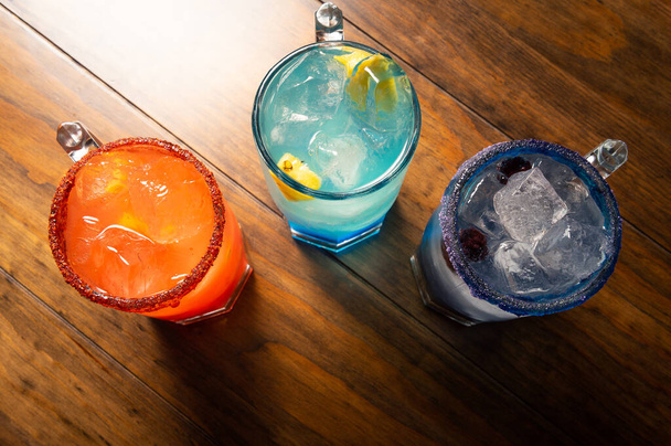 Kleurrijke cocktails op houten ondergrond. Frute alcoholische cocktails. Kleurrijk drankconcept op houten tafel - Foto, afbeelding