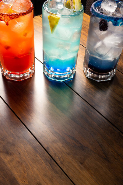 Ahşap arka planda renkli kokteyller. Frutal alkollü kokteyller. Ahşap masada renkli içki konsepti - Fotoğraf, Görsel