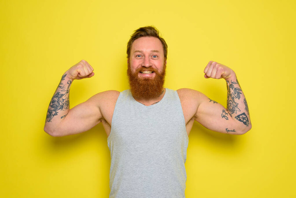 Hombre con barba y tatuajes muestra con orgullo su músculo - Foto, Imagen