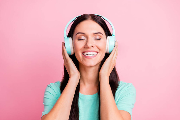 Portrait of young beautiful excited smiling positive girl in headphones listening music isolated on pink color background - Fotó, kép