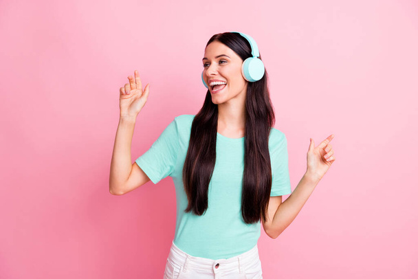 Photo of young beautiful lovely excited smiling cheerful girl in headphones dancing isolated on pink color background - Fotó, kép