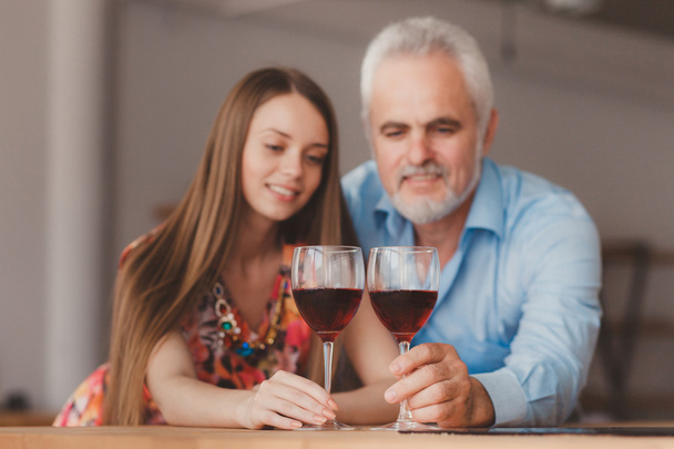 young girl and senior man holding wine glasess - Valokuva, kuva