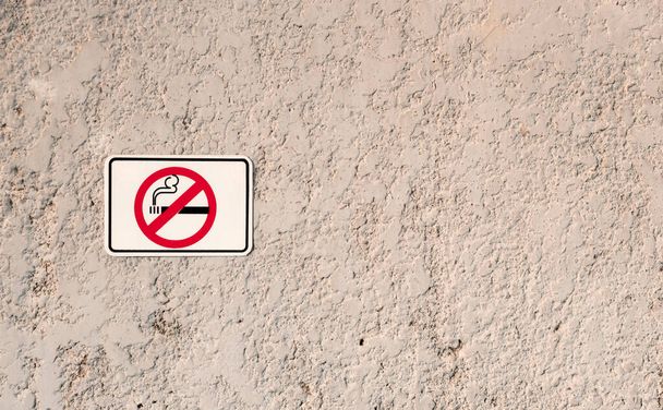No smoking white sign with cigarette symbol on grunge stone texture wall, smoke strictly prohibited area - Foto, Imagem