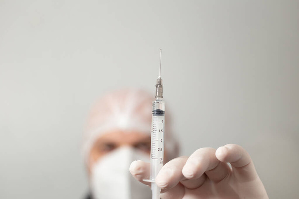 Ein Arzt in der Hand eine Spritze mit Medikamenten. Spritze mit Covid-19-Impfstoff. - Foto, Bild