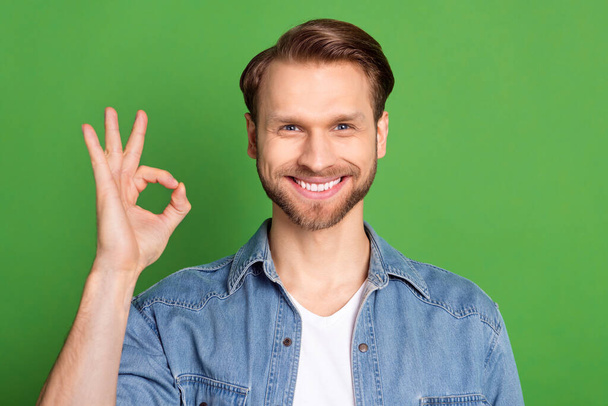 Photo portrait of man showing okay gesture smiling isolated on bright green color background - Photo, image
