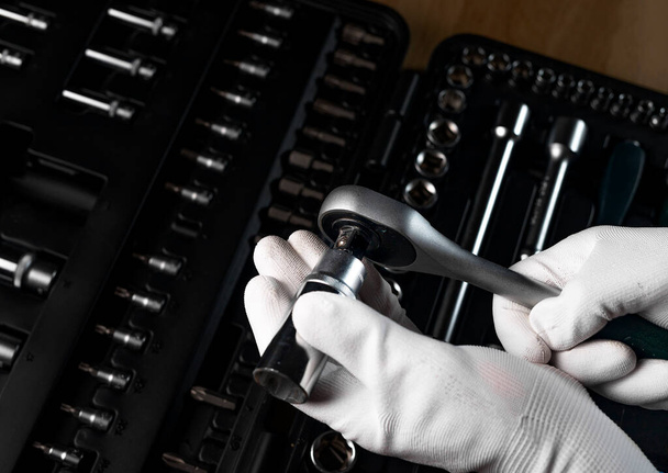 Male hand in building glove with socket ratchet handle and metal steel hex socket, hexagon metal head. Car repair metal tool, close up - Φωτογραφία, εικόνα