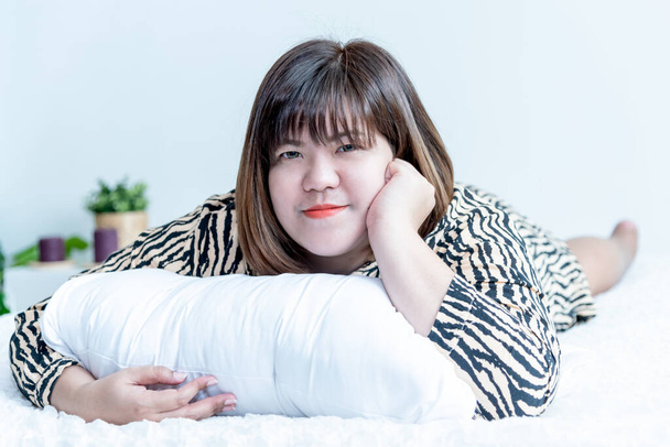 Ritratto immagini di bella asiatica donna grassa sdraiata e riposare sul letto bianco, nella sua camera da letto che felicemente, alla gente e rimanere a casa concetto. - Foto, immagini