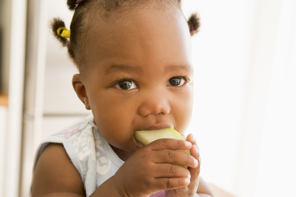 Young girl eating apple indoors - Valokuva, kuva