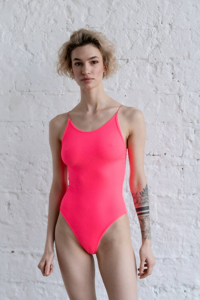 young beautiful woman pose in pink bodysuit in studio - Photo, Image